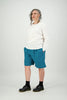 Woman wears white shirt with horizontal design line paired with teal shorts Citizen Women 