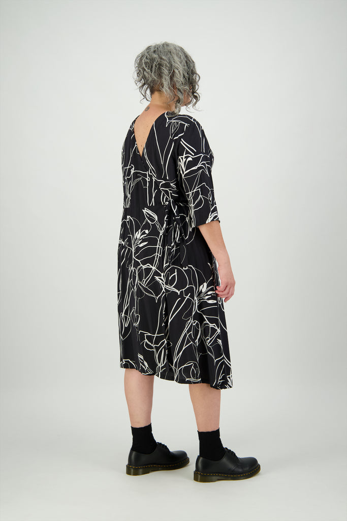 Back view woman wears knee length floral black and white dress Citizen Women